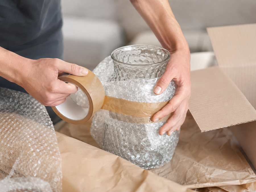 Mains protégeant un objet fragile avec papier et adhésif